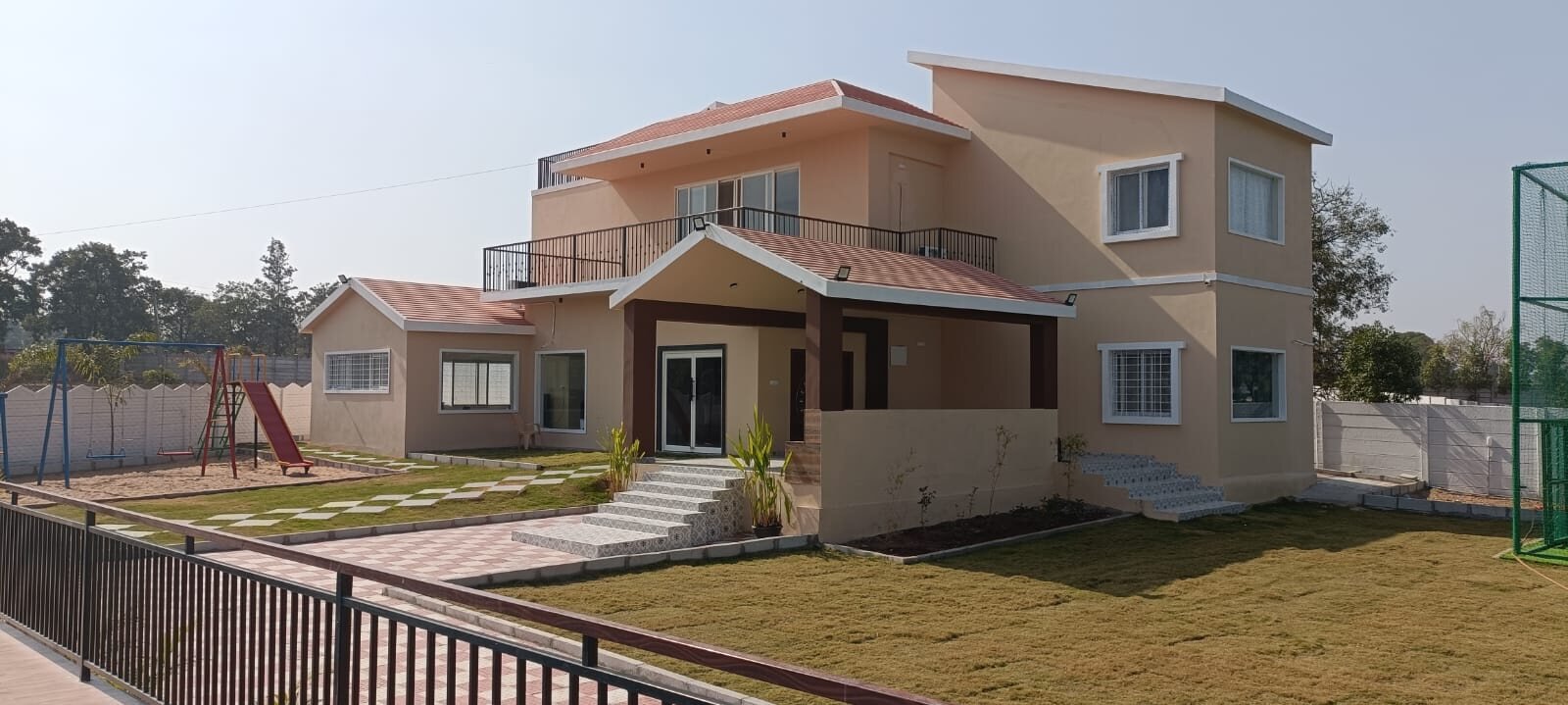 The front of the farmhouse with its lawn and play area