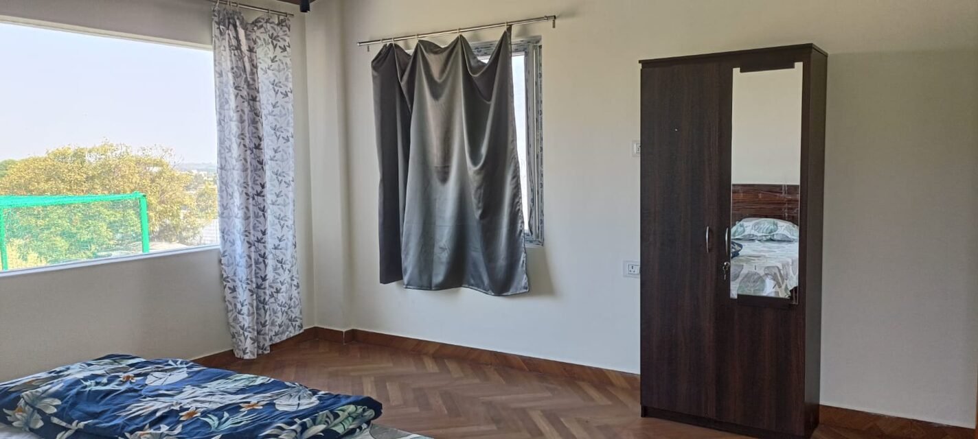 A bedroom with wardrobe and corner windows